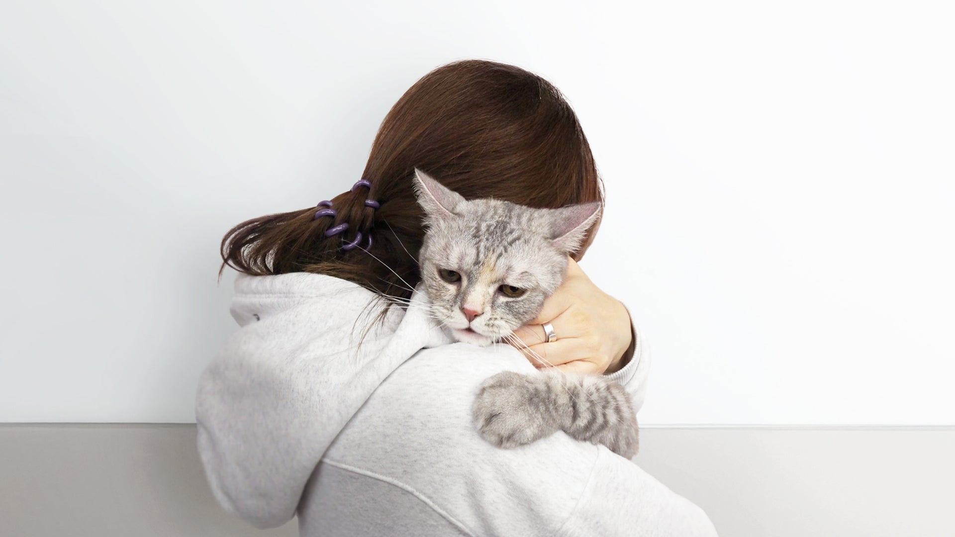 Greycoat brand image showing a woman gently holding a kidney-compromised cat, representing emotional support and care for feline kidney health.